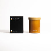 The Solarium Candle in an amber glass jar with its printed box