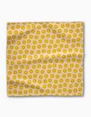 Single Sunny Sun napkin laid flat, rows of golden suns across a butter-yellow ground