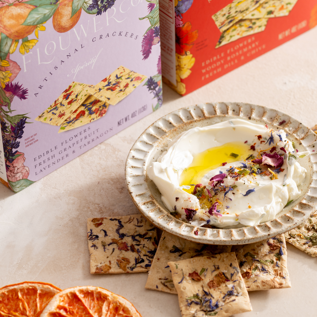 The Apéritif box beside a bowl of labneh dip garnished with olive oil and edible flowers