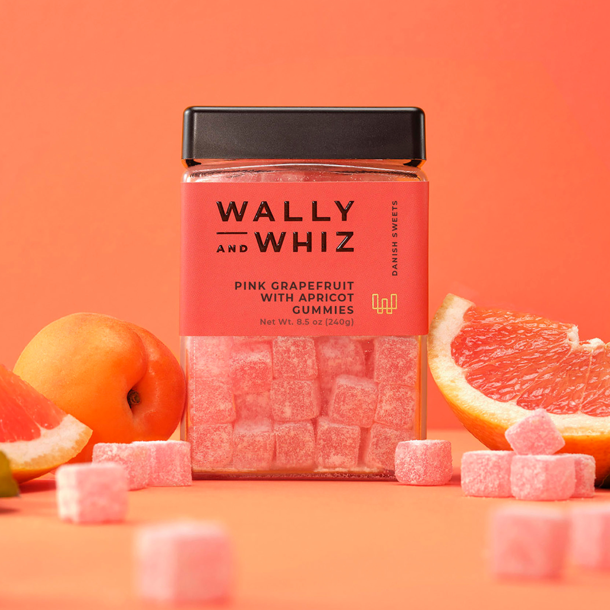 Wally and Whiz pink grapefruit with apricot gummies in a coral 8.5 oz jar, surrounded by grapefruit and apricots
