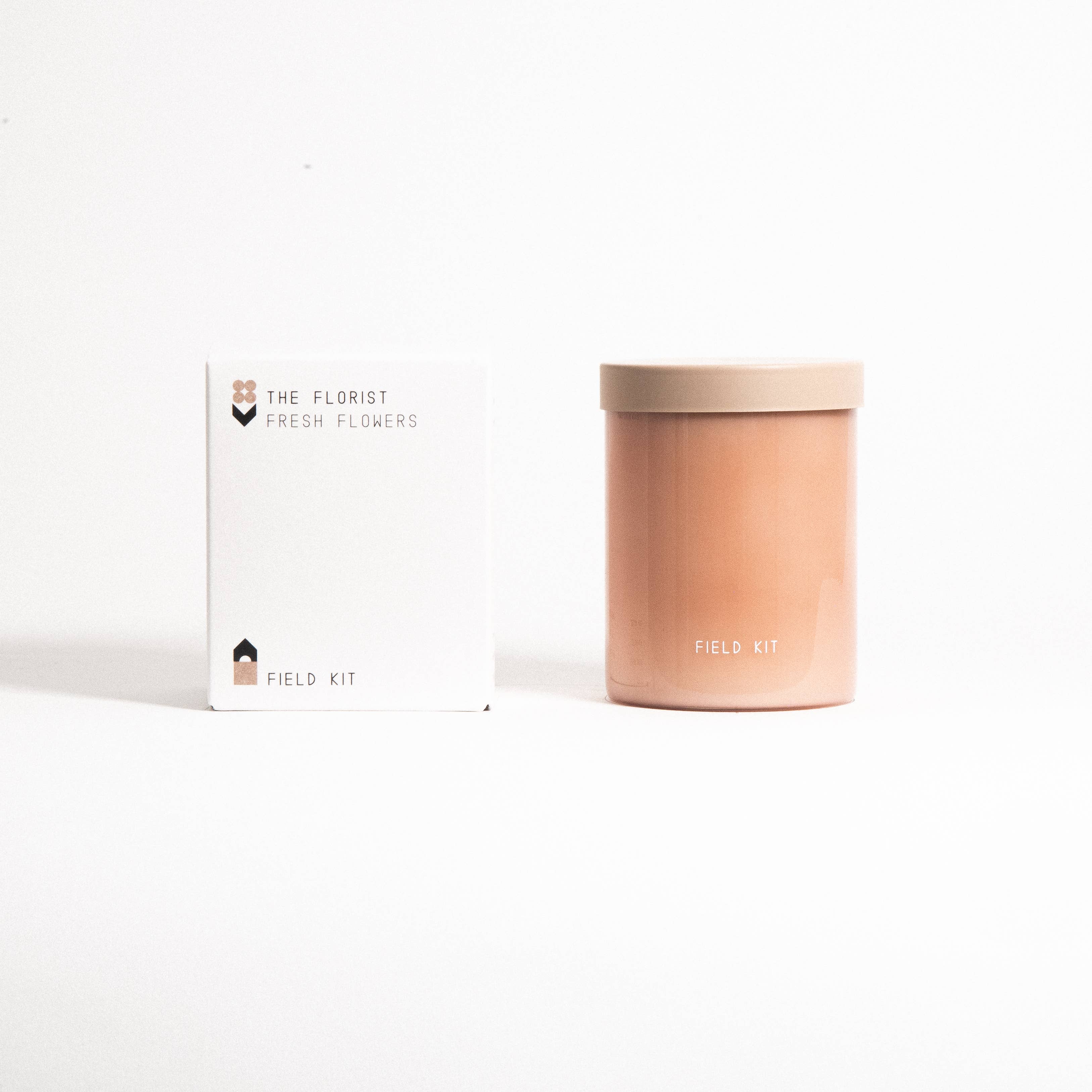 The Florist Candle in a blush glass jar with its printed box