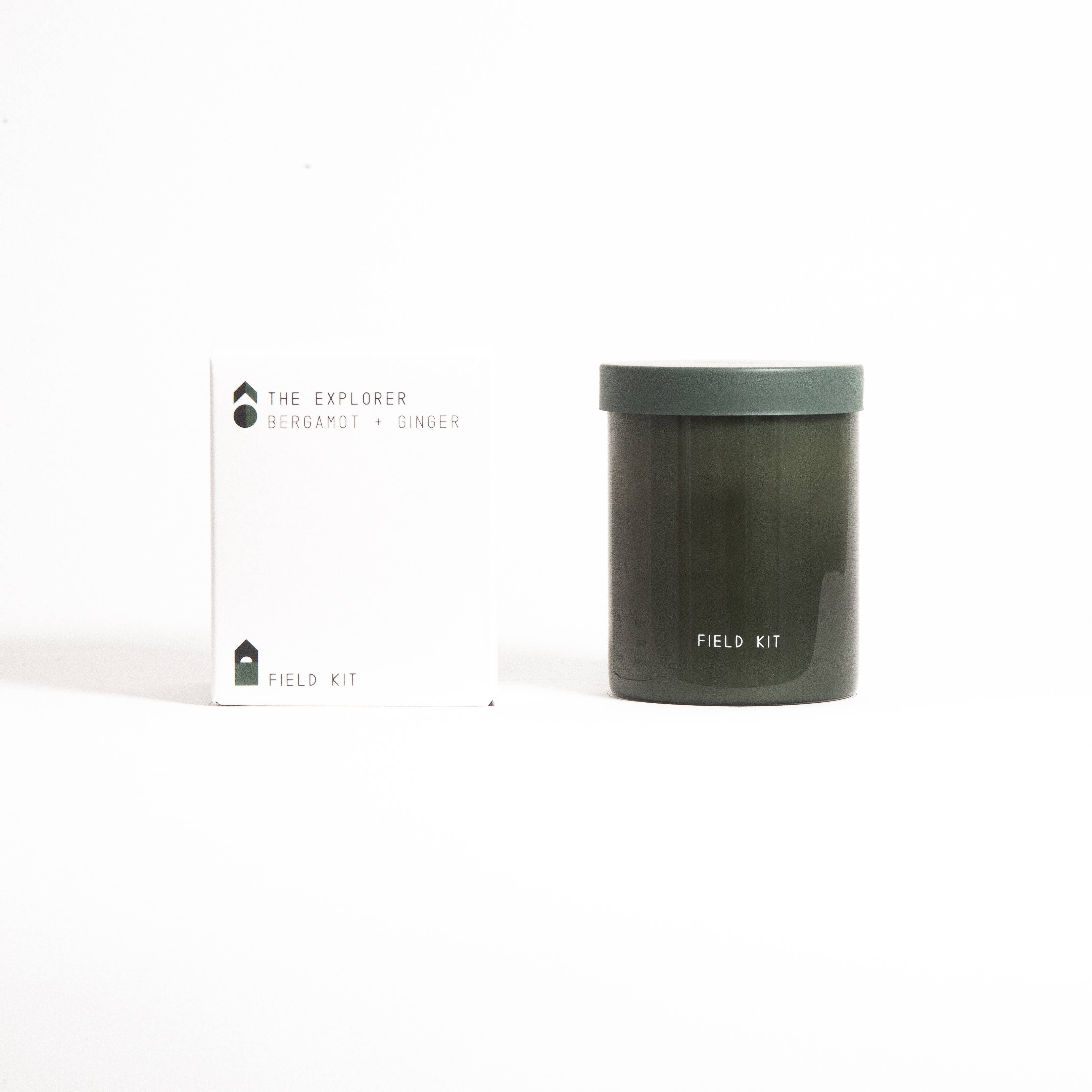 The Explorer Candle in a dark green glass jar with its printed box