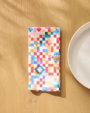 Patchwork Geo napkin folded on a wooden table beside a white plate