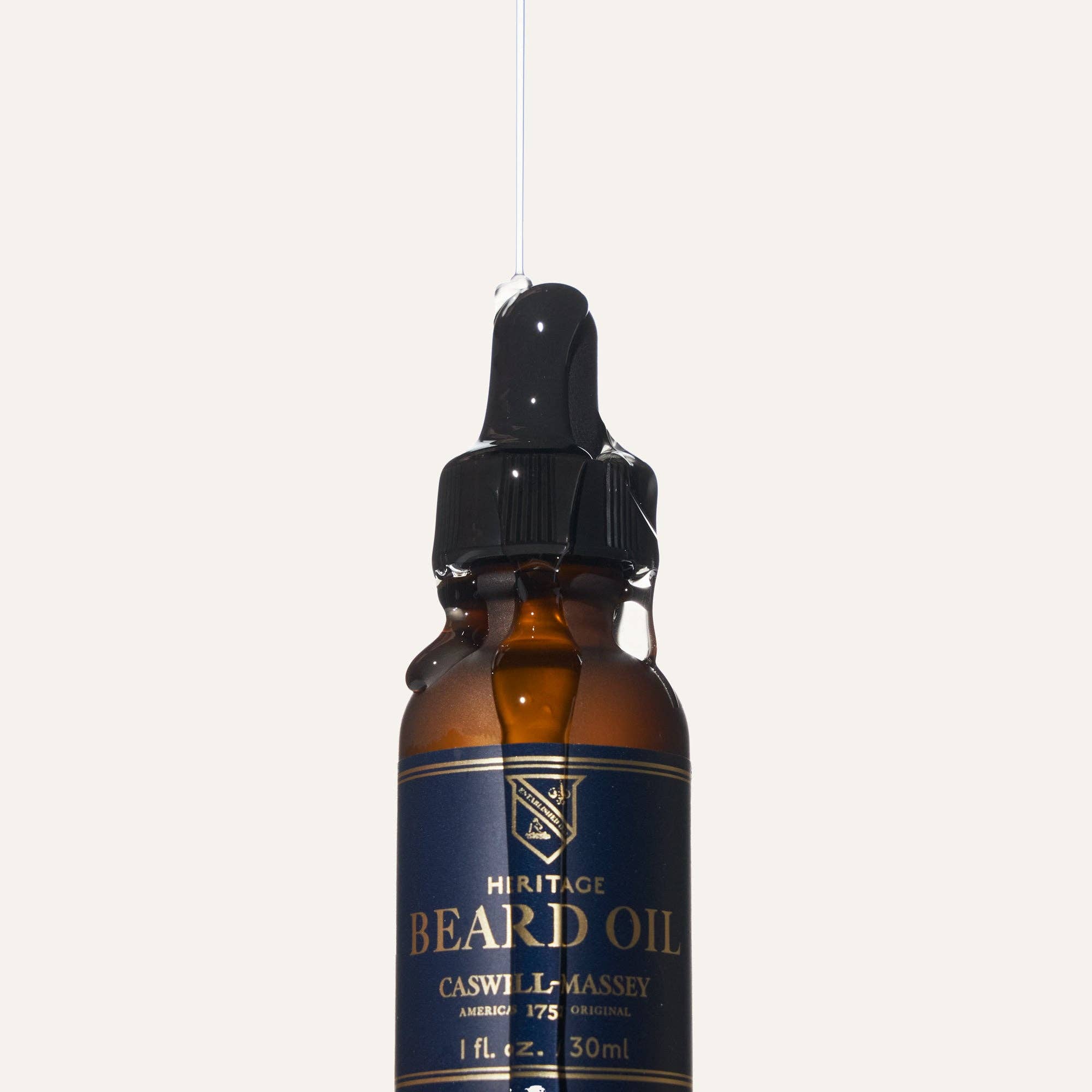 Close-up of the beard oil dropper with a strand of oil drawn from the bottle