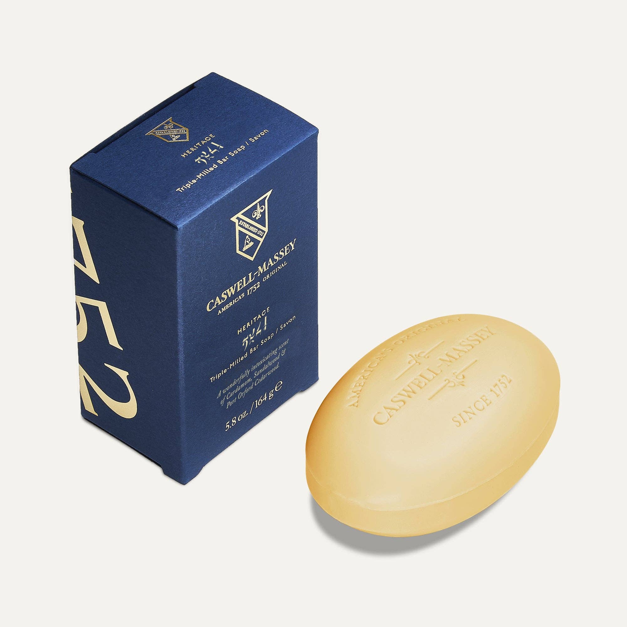 Caswell-Massey 2571 bar soap, a cream oval bar embossed with the crest, beside its navy and gold box