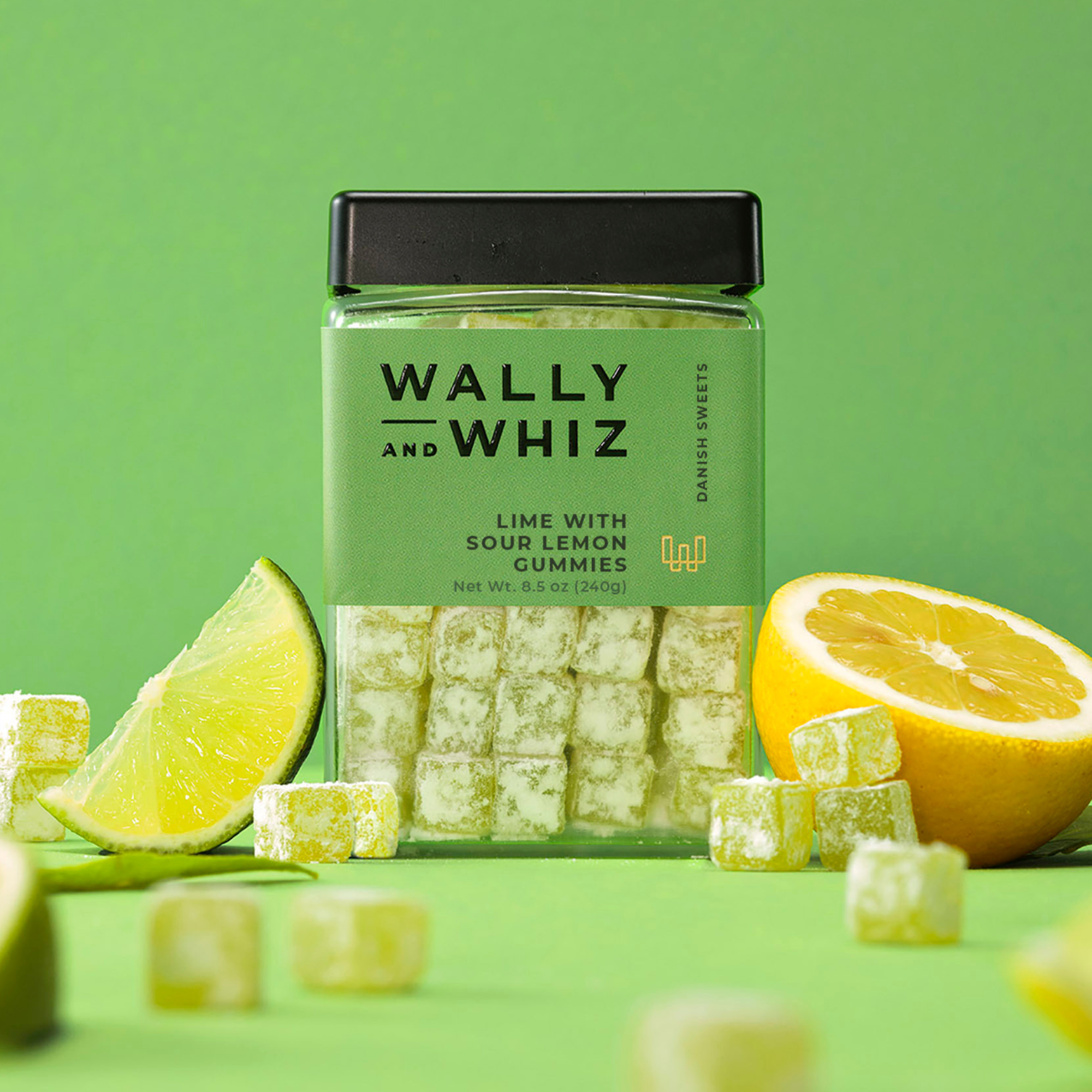 Wally and Whiz lime with sour lemon gummies in a green 8.5 oz jar, surrounded by lime and lemon