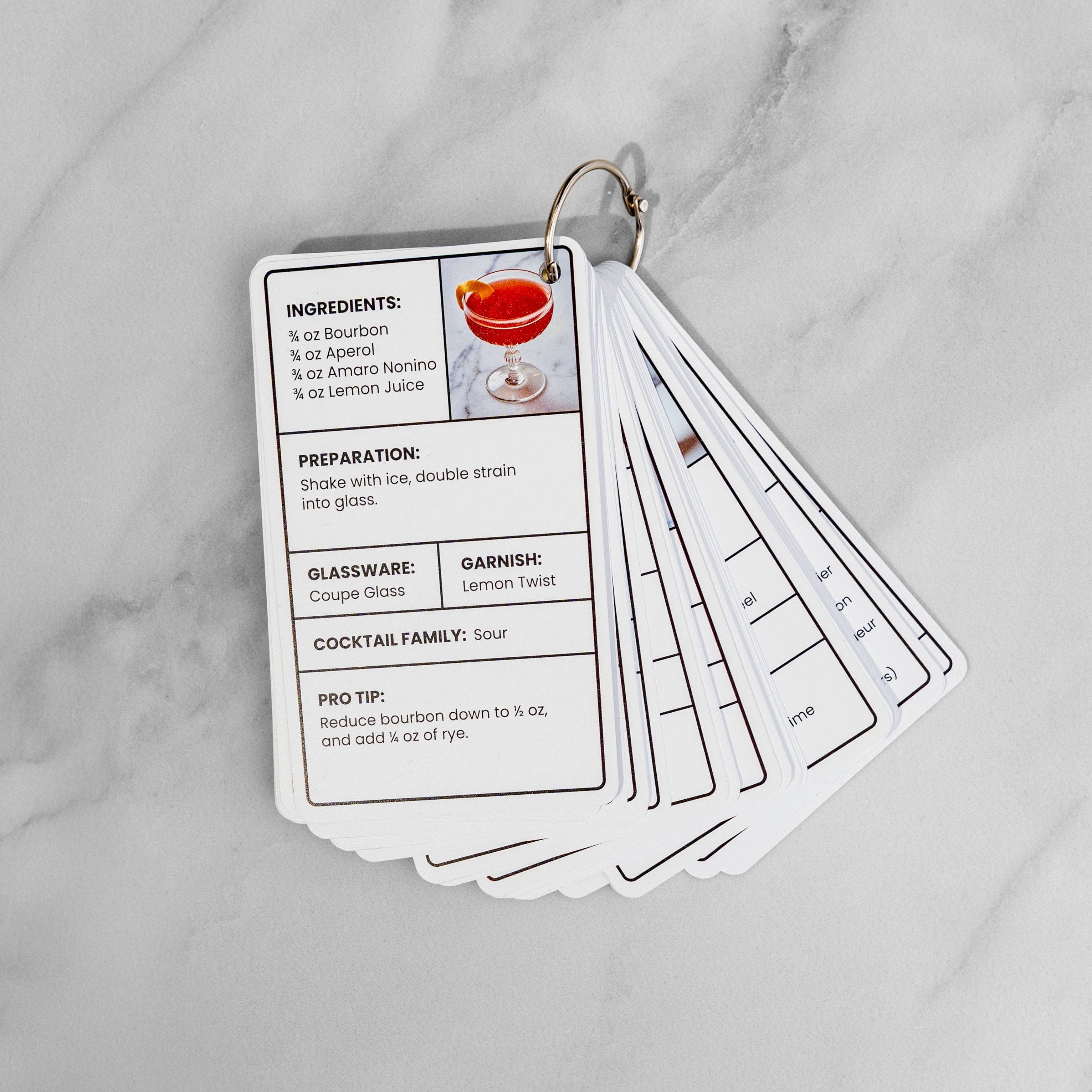 The full deck fanned open on its metal ring, showing the Paper Plane recipe card on top