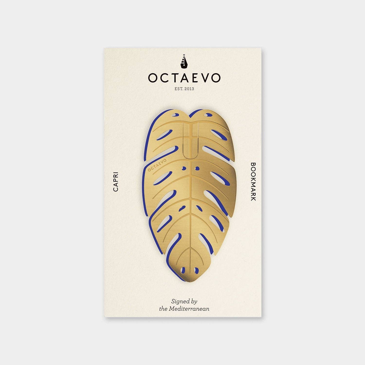 OCTAEVO Capri bookmark, brass monstera leaf shape with blue detail on its printed card