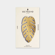 OCTAEVO Capri bookmark, brass monstera leaf shape with blue detail on its printed card