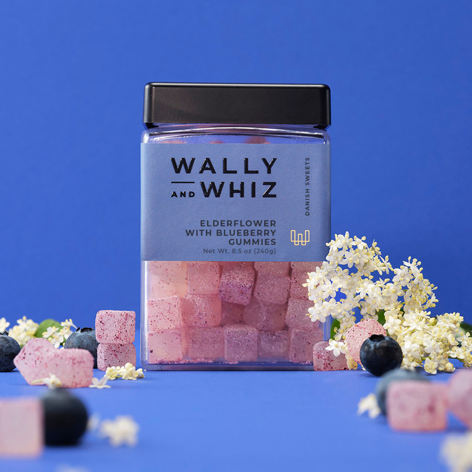 Wally and Whiz elderflower with blueberry gummies in a blue 8.5 oz jar, with elderflower blossoms and blueberries