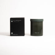 The Greenhouse Candle in a dark green glass jar with its printed box