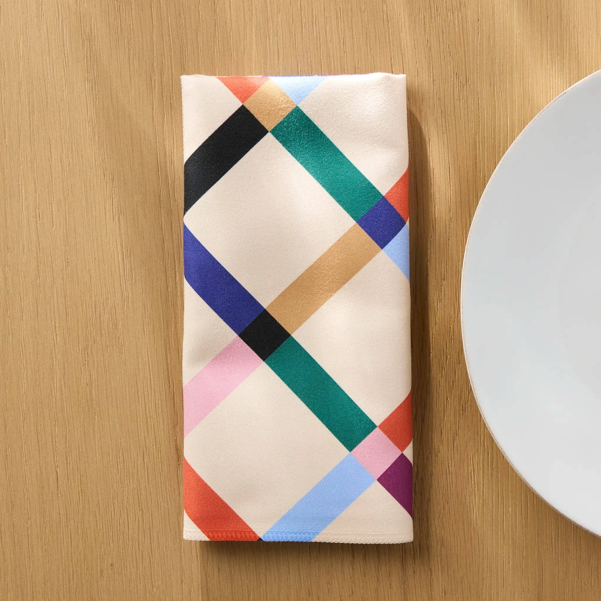 Cool Grid napkin folded lengthways on a wooden table beside a white plate