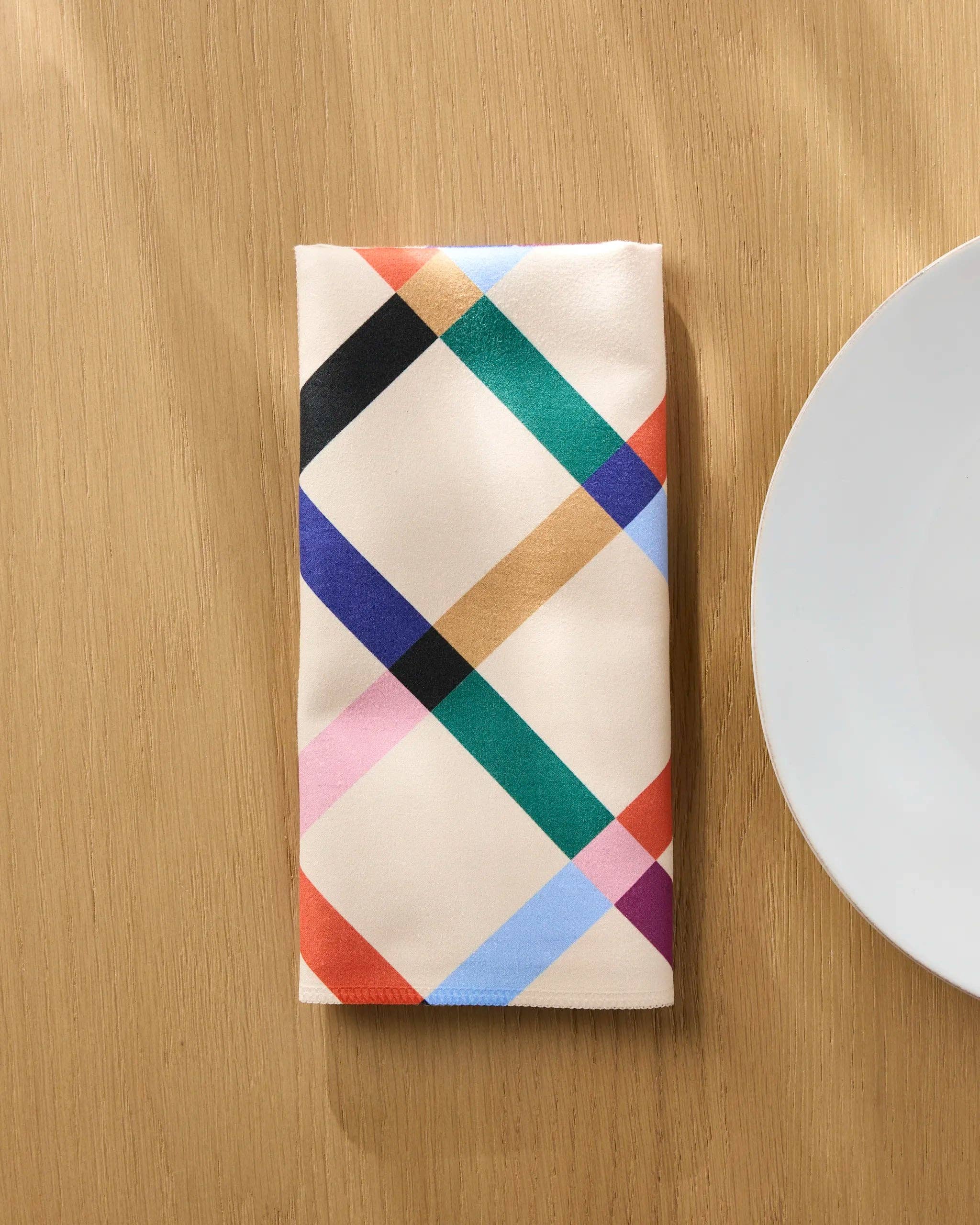 Cool Grid napkin folded lengthways on a wooden table beside a white plate