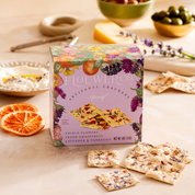 The Apéritif box styled on a table with olives, cheese, dried orange slices and fresh lavender