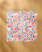 Patchwork Geo napkin opened flat on a wooden table, showing the full watercolour grid