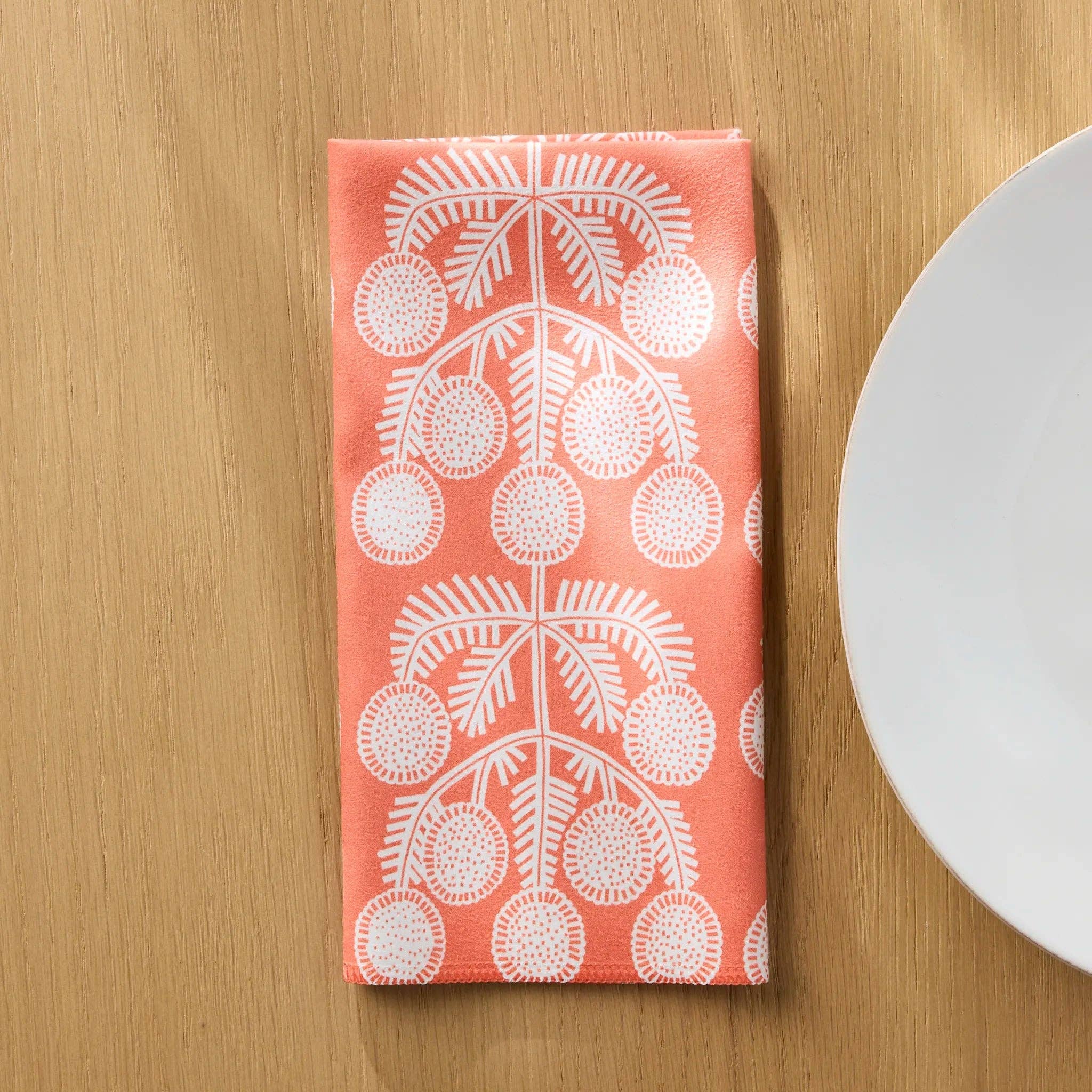 Graphic Daisies napkin folded on a wooden table beside a white plate