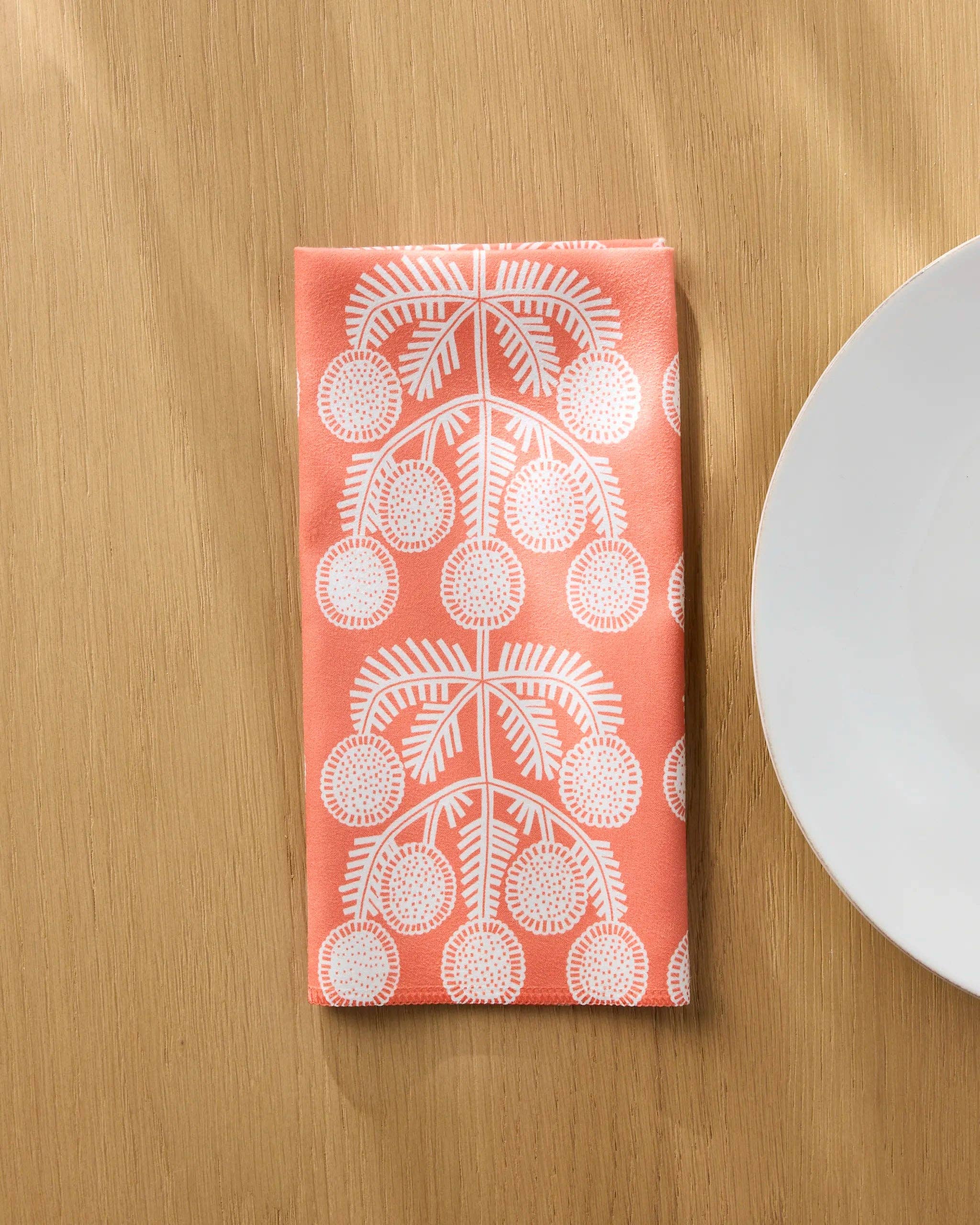 Graphic Daisies napkin folded on a wooden table beside a white plate