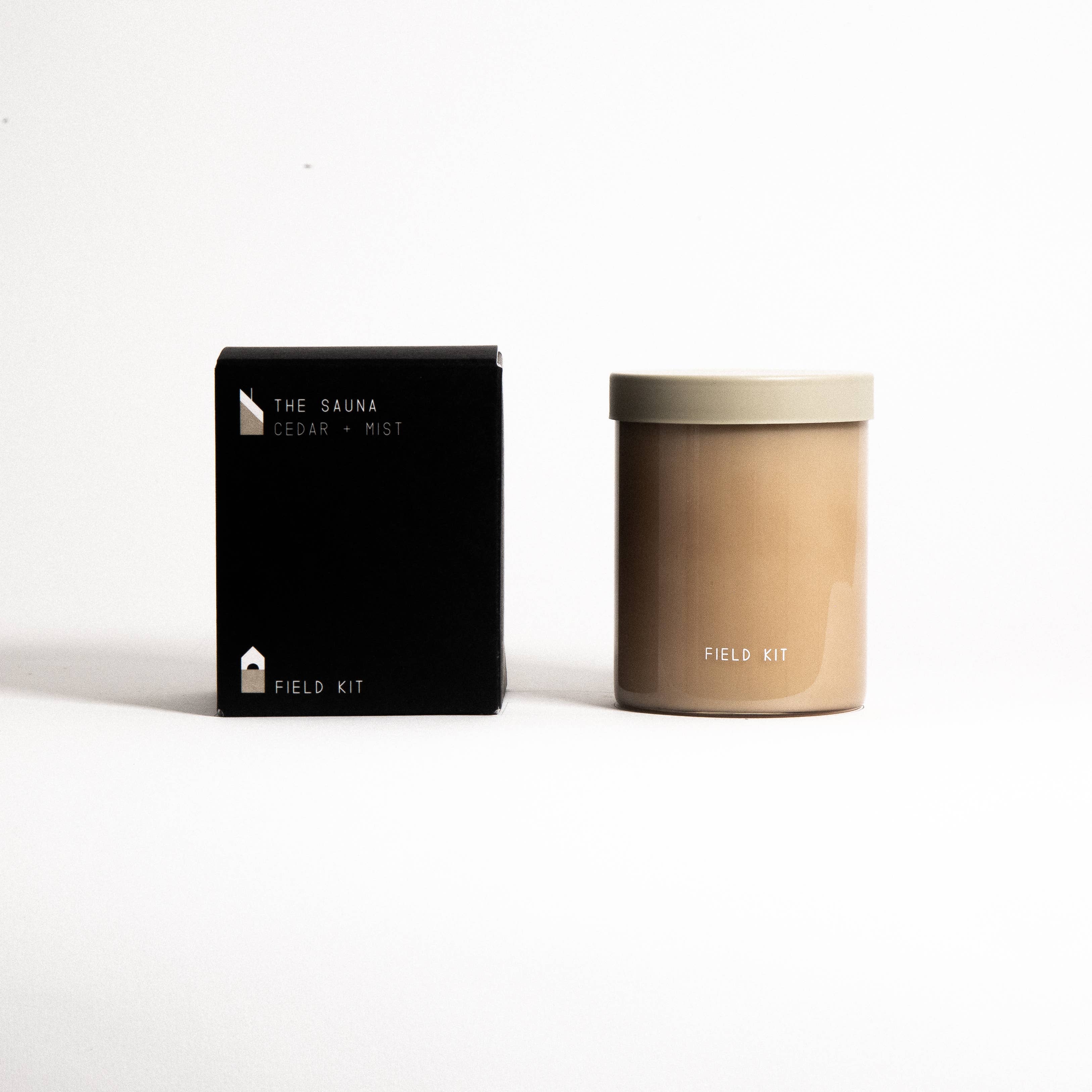 The Sauna Candle in a tan glass jar with its printed box