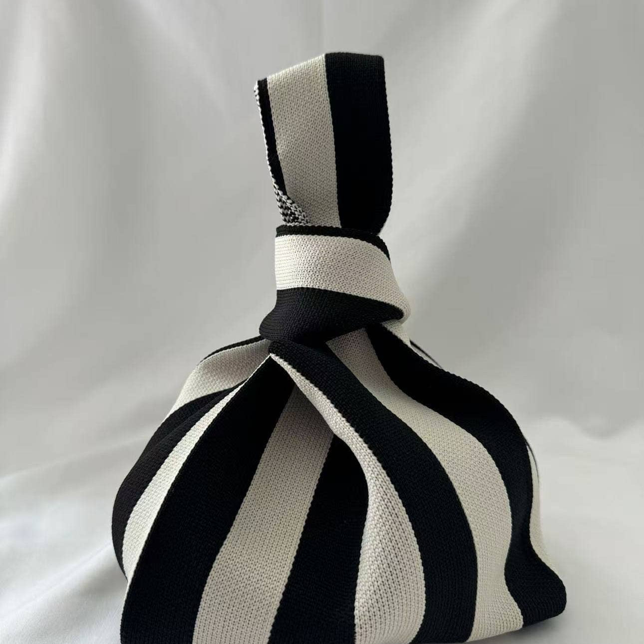 Black and cream vertical stripe knitted bag with the handles knotted at the top