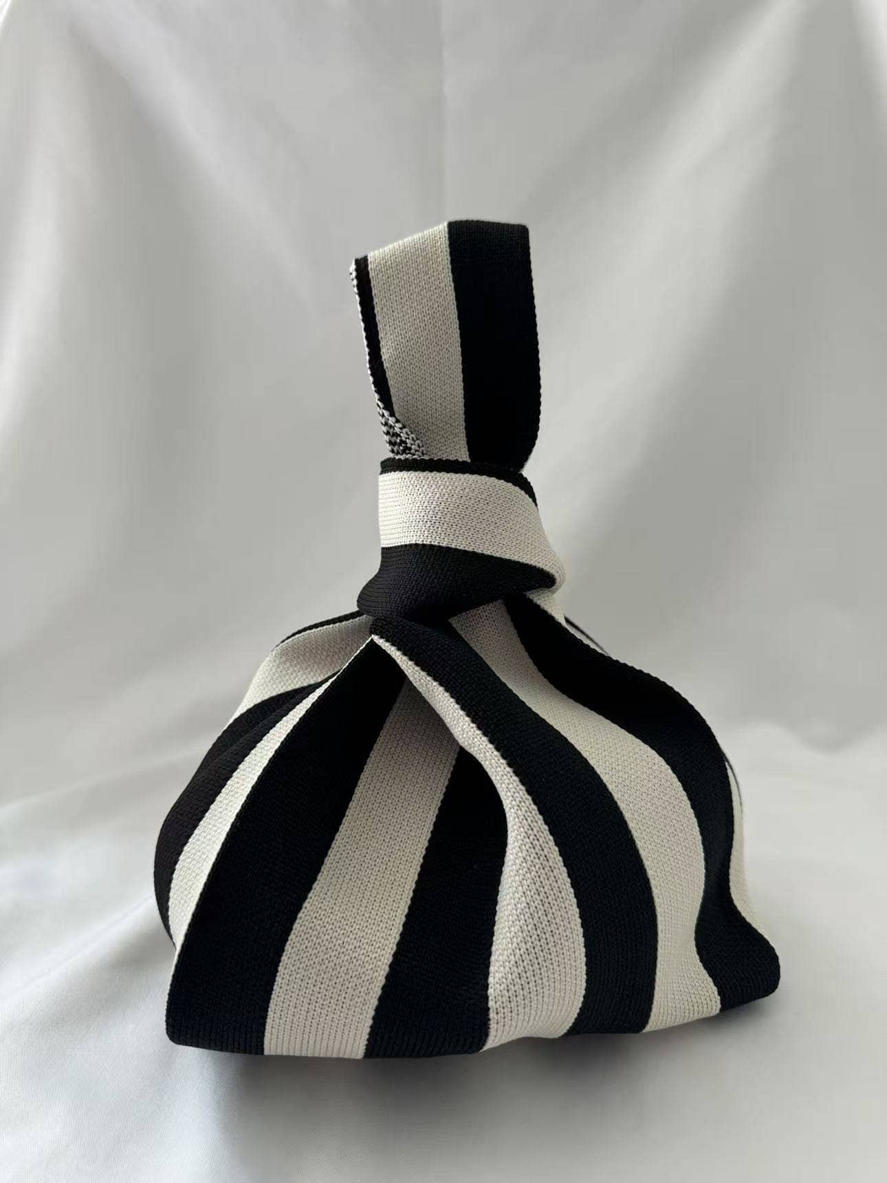 Black and cream vertical stripe knitted bag with the handles knotted at the top