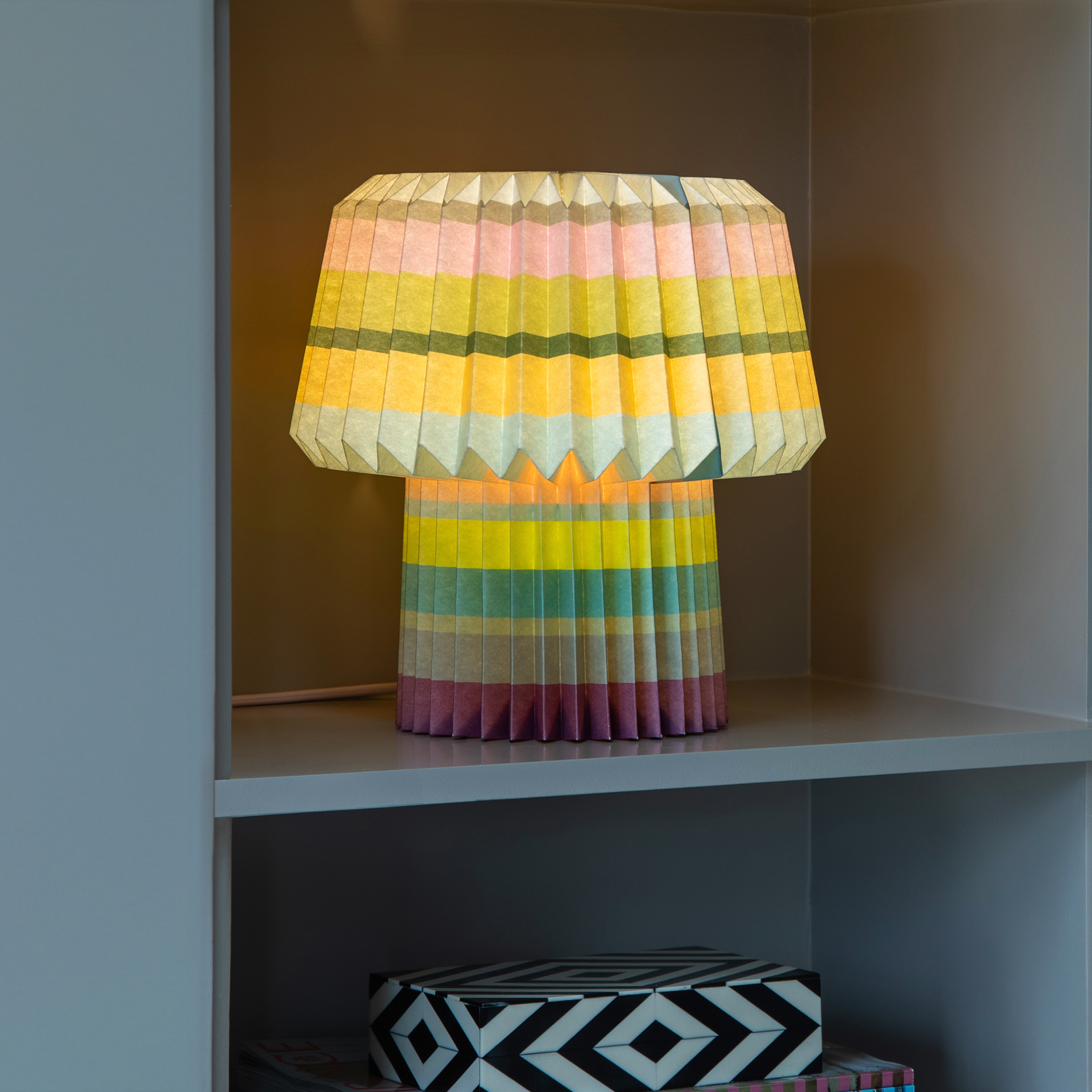 The stripes lamp lit in a white alcove shelf above a patterned box