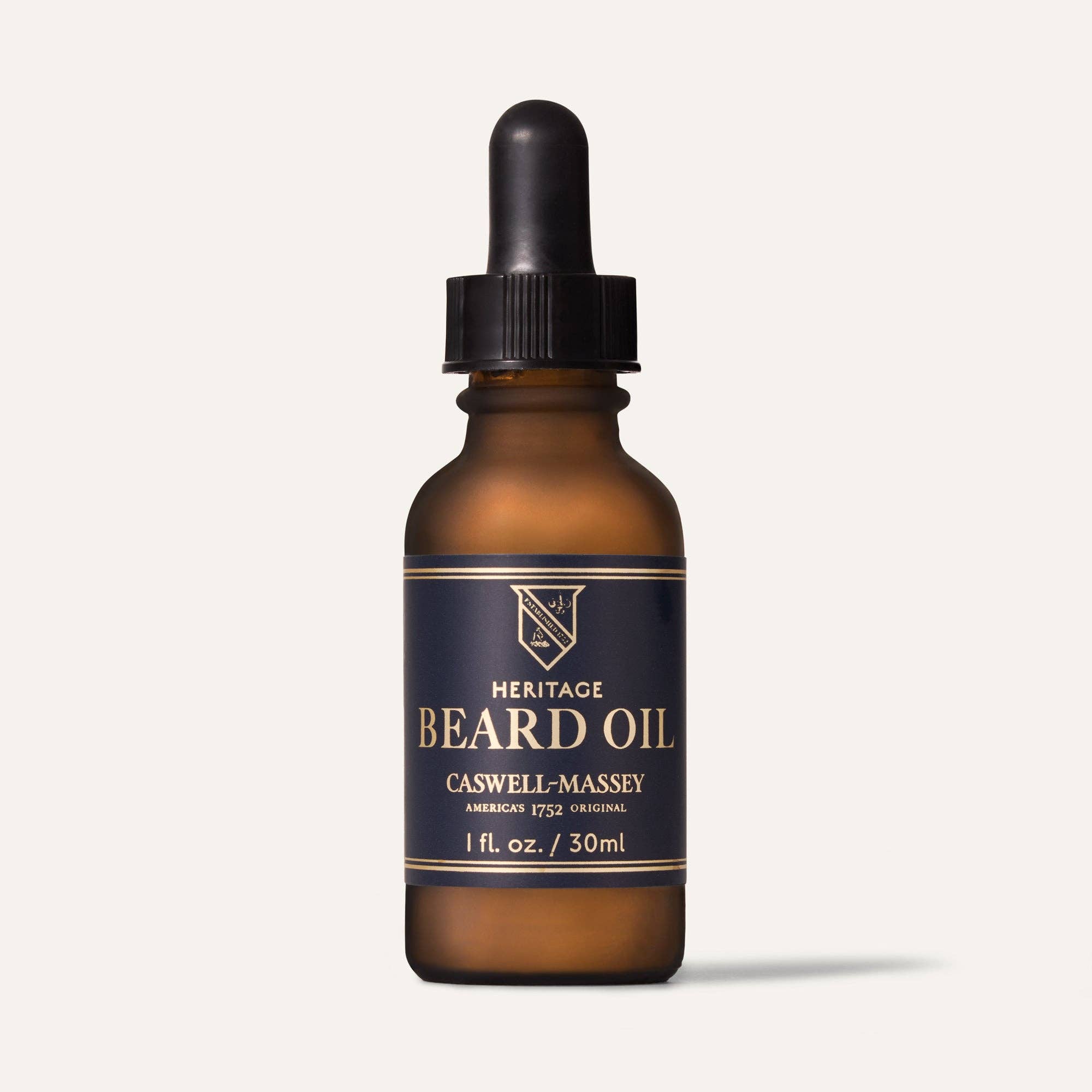 Caswell-Massey Heritage Beard Oil in a 1 fl oz amber glass bottle with a black dropper and navy label
