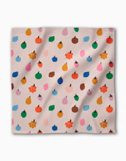 Single Fruit Basket napkin laid flat, small apples, pears and blossoms on pale blush