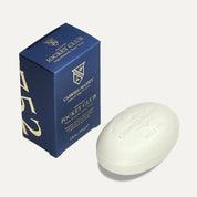 Caswell-Massey Jockey Club bar soap, a cream oval bar embossed with the crest, beside its navy and gold box
