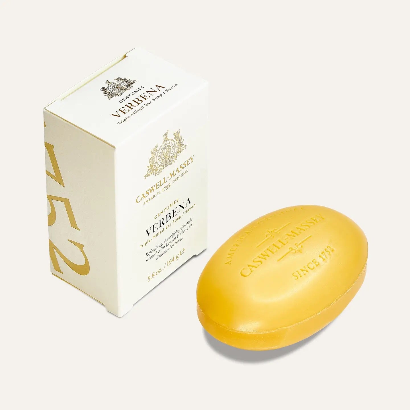 Caswell-Massey Verbena bar soap, a pale yellow oval bar embossed with the crest, beside its cream and gold box