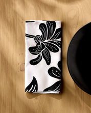 Giant Lush Floral napkin folded on a wooden table beside a white plate
