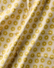 Close-up of the Sunny Sun print, small yellow sunbursts on a cream ground