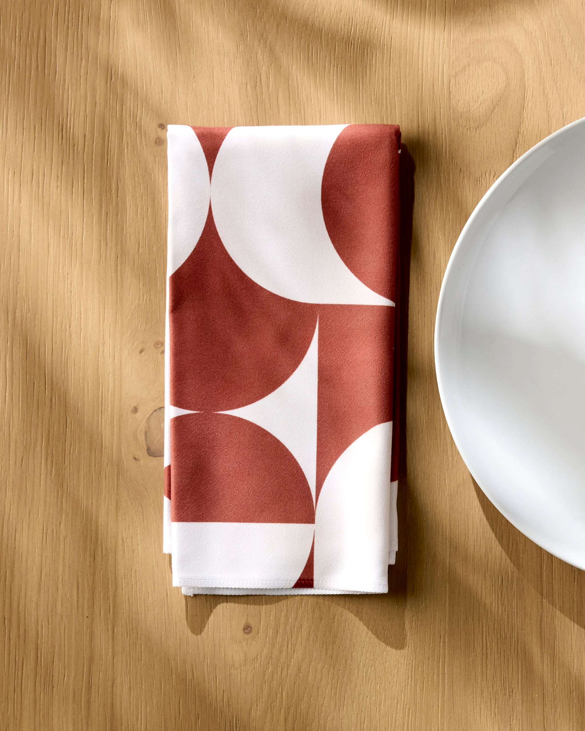 Circle Playground napkin folded on a wooden table beside a white plate