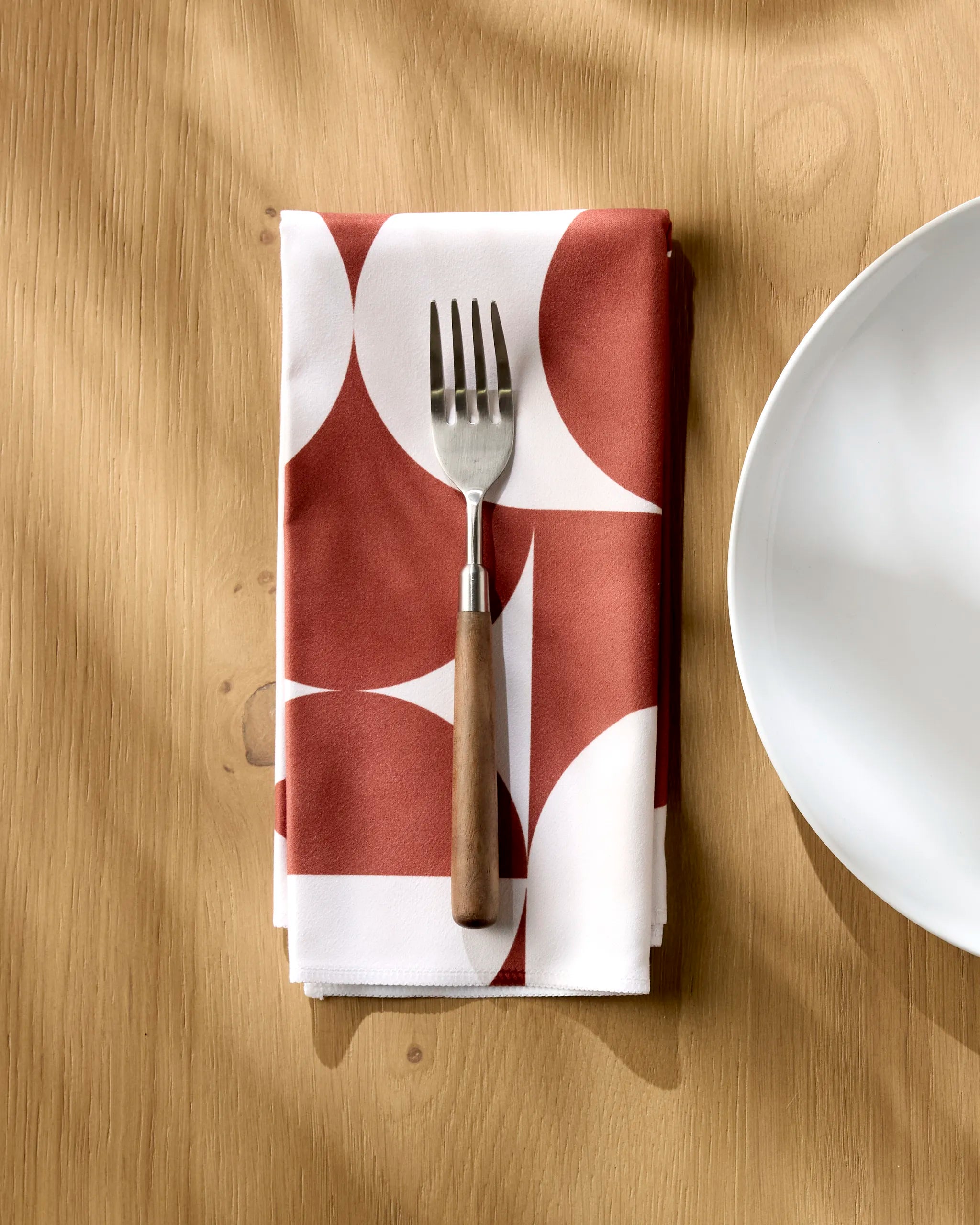 Circle Playground napkin folded on a wooden table with a fork resting on top