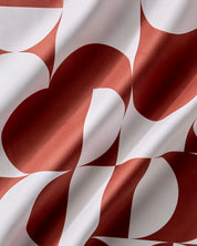 Close-up of the Circle Playground print, rust red and white curves and semicircles on draped fabric
