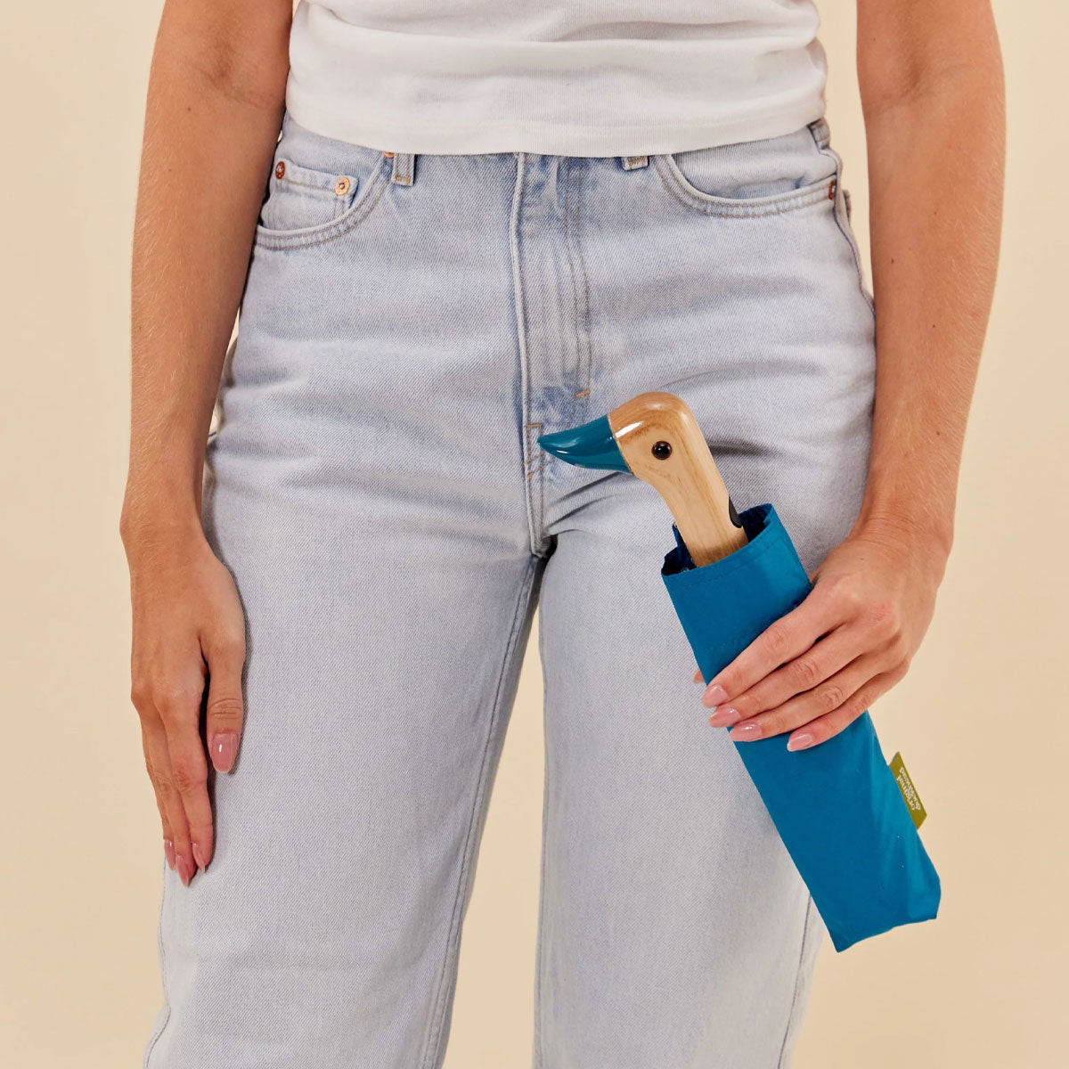 Duck Umbrella closed in its sleeve, held in hand, showing the carved birch duck handle