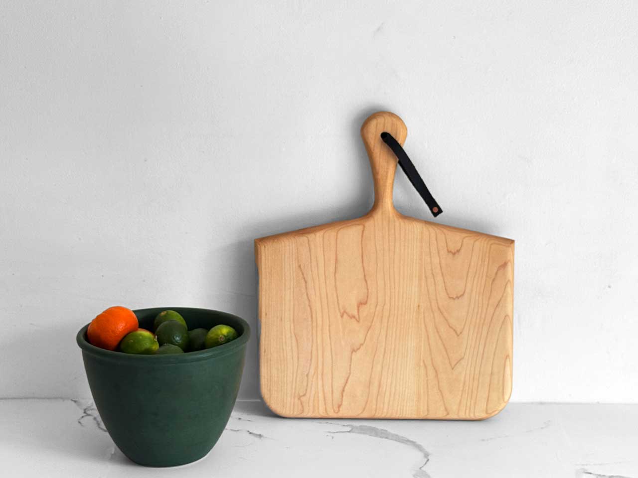 Norr Board in Maple standing beside a green bowl of citrus