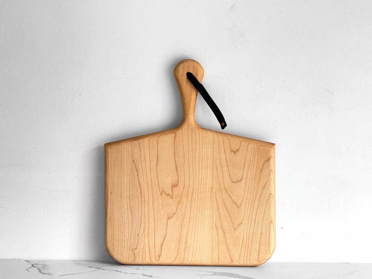KHEM Studios Norr Board in Maple, squared paddle shape with a tapered handle and leather strap