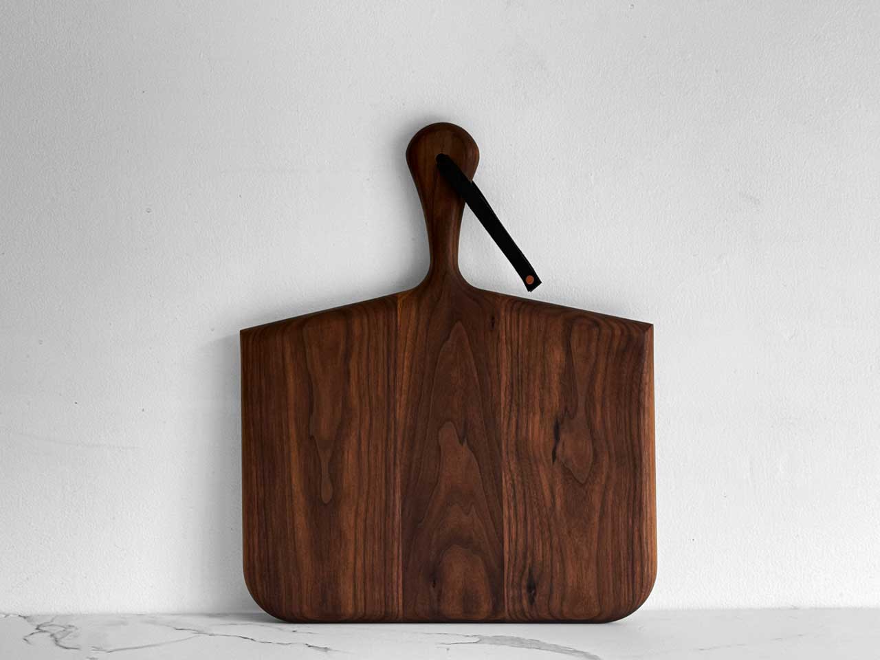 KHEM Studios Norr Board in Walnut standing upright with its leather hanging strap