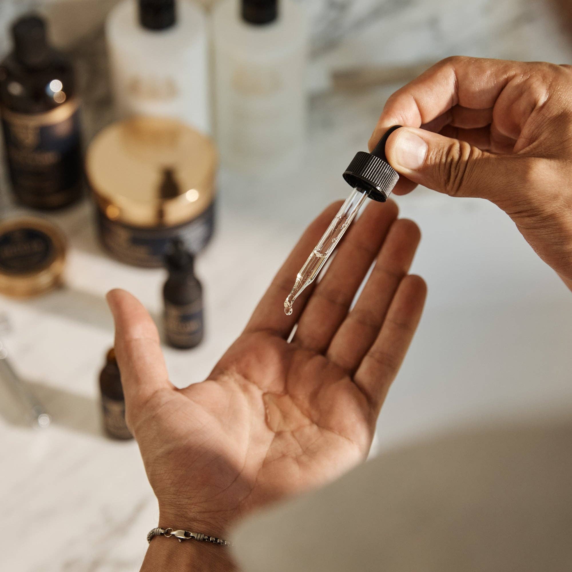 A dropper of beard oil being dispensed into an open palm at a bathroom counter
