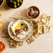 No. 1 crackers arranged around a bowl of whipped cheese topped with edible flowers and olive oil