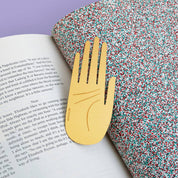 OCTAEVO Hamsa brass bookmark marking a page in an open book