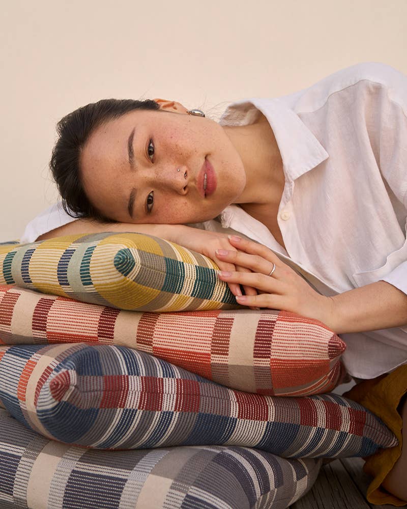 A woman resting on a stack of Mungo Skipping Block Cushions
