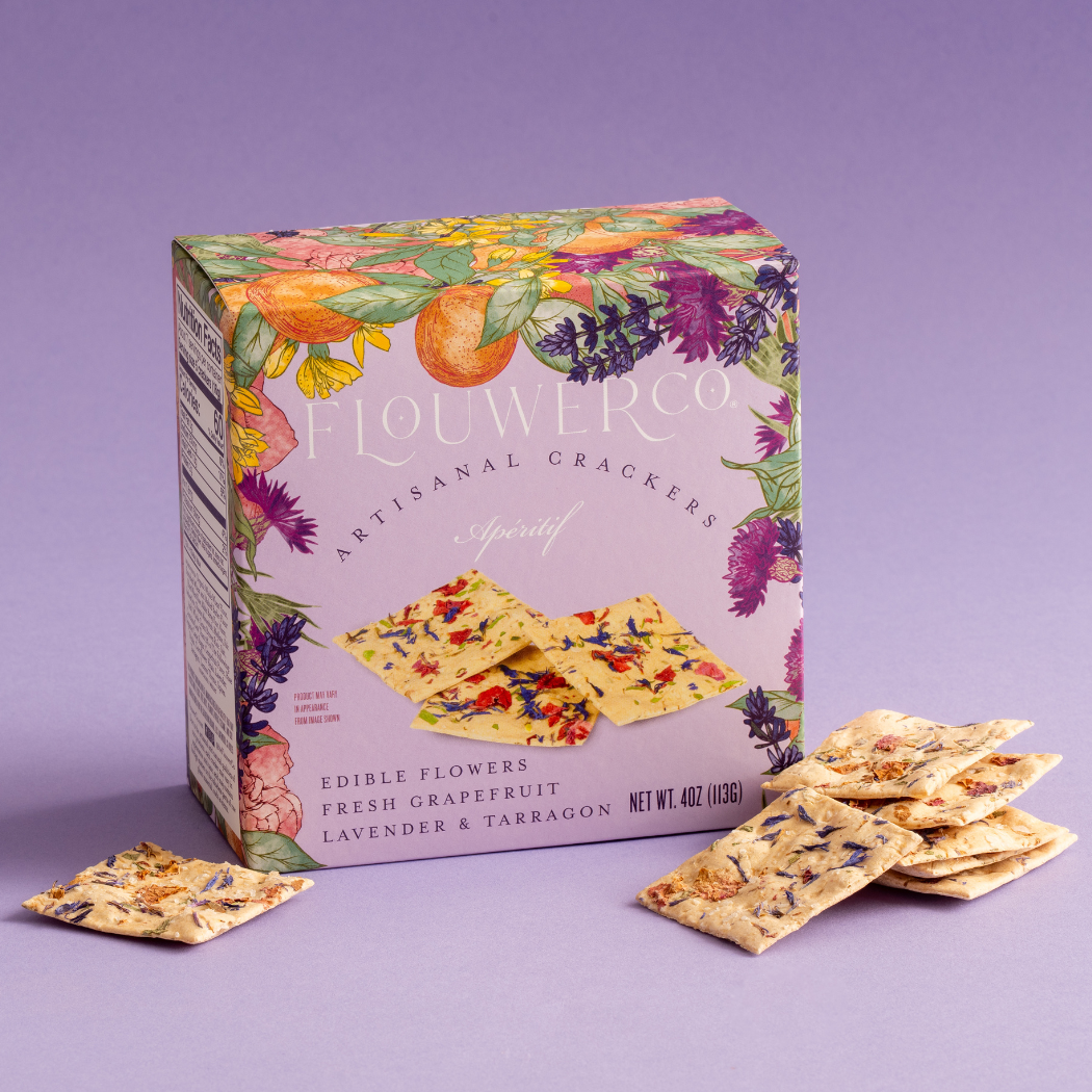 Flouwer Co. Apéritif crackers in a lavender floral box with flower-flecked crackers stacked beside it