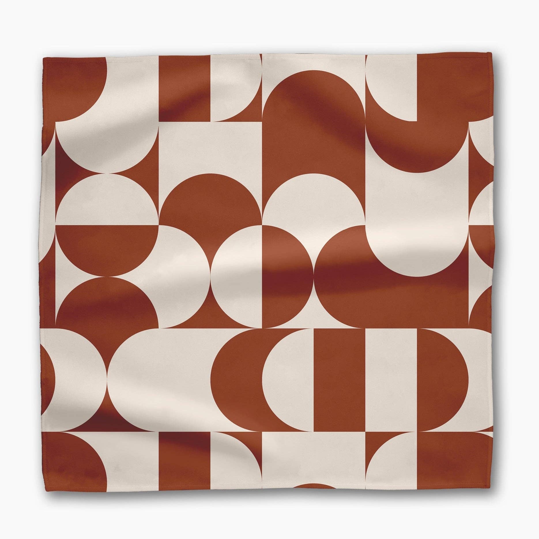 Single Circle Playground napkin laid flat, terracotta and cream half-circles and arcs