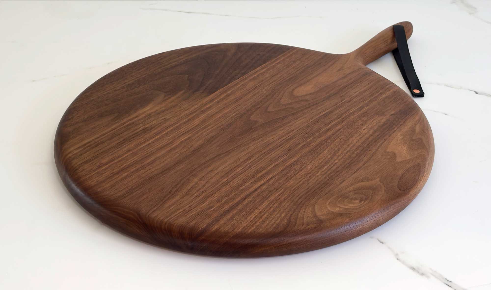 Round Board in walnut by KHEM Studios, on a marble surface